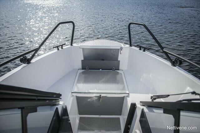 View from the bow of a modern boat showcasing the deck, storage compartment, and shimmering water in the background.